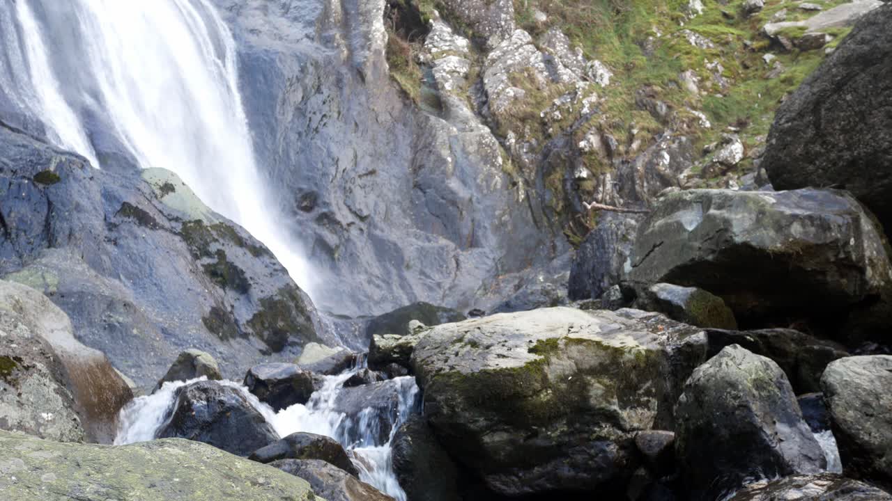 cascada rocosa que fluye hacia rocas de río irregulares y cantos rodados a la izquierda dolly lento