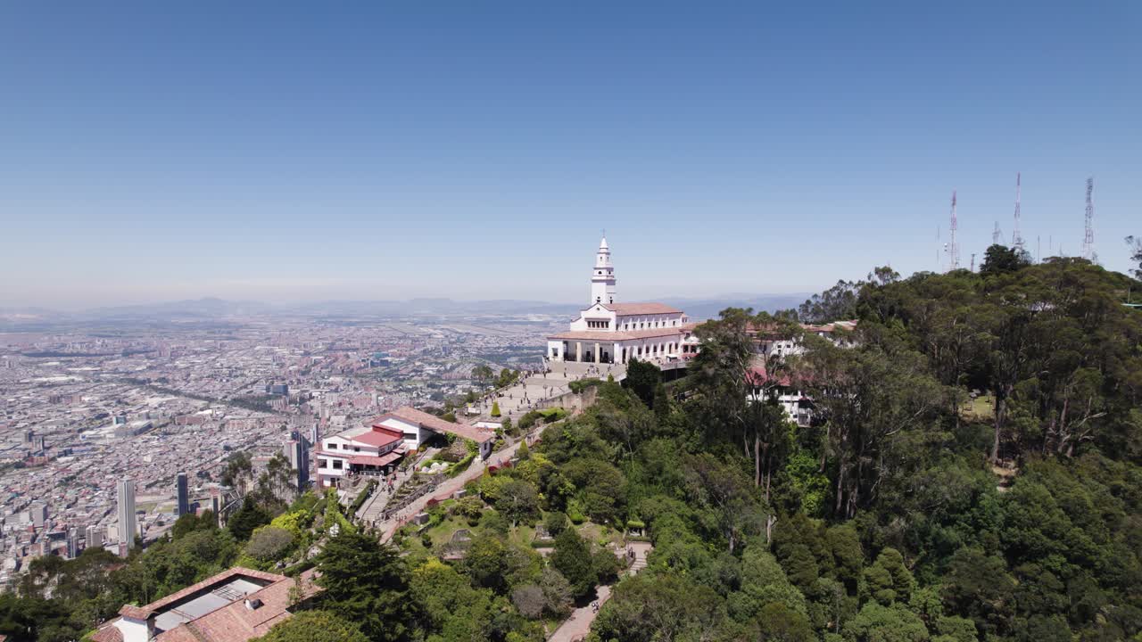 tomada aérea en órbita del santuario de monserrate en la cima de la colina, el paisaje urbano de bogotá en el fondo, colombia