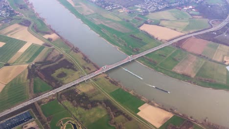 view from an airplane flying above a big bridge , a river and fields in europe