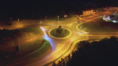 time lapse aerial view of a roundabout illuminated by streetlights, with vivid car light trails highlighting traffic motion