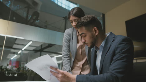 two business professionals discuss documents in an office