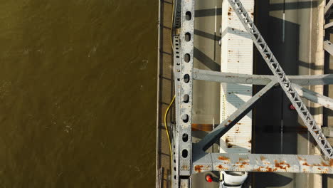 Top-down-view-of-West-Memphis-Delta-Regional-River-Park-with-cars-crossing-bridge,-strong-shadow,-sunny-day