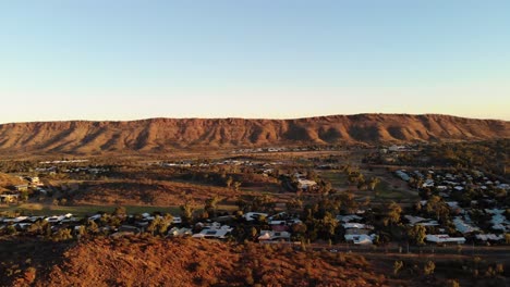 left trucking drone shot of the mountains and town in alice springs, australia