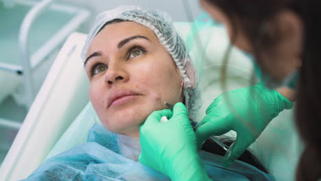 beautician does filler injection into beautiful lady cheek