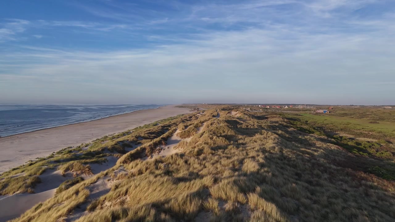 Energisk drönarflygning som sveper över dynvegetation mot stranden