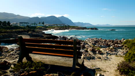 Bench-on-rocky-coastline-overlooking-ocean,-Windsor-Bay,-Hermanus