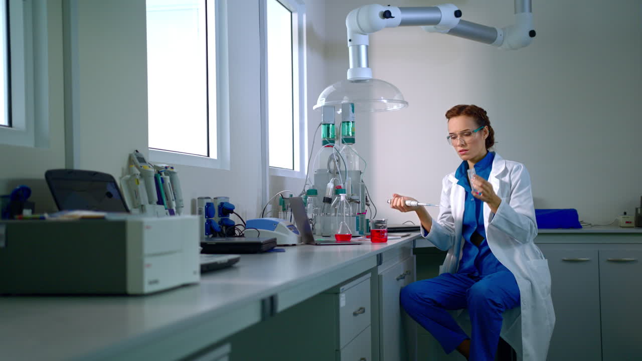Chemička pracuje s kapalinou v chemické laboratoři. Chemický výzkum.