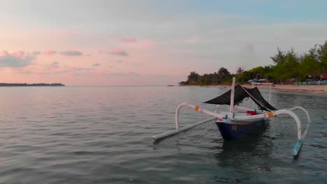 Luftaufnahme-Einer-Tropischen-Insel-Mit-Einer-Drohne,-Die-Bei-Sonnenuntergang-An-Einem-Traditionellen-Boot-Vorbeifährt