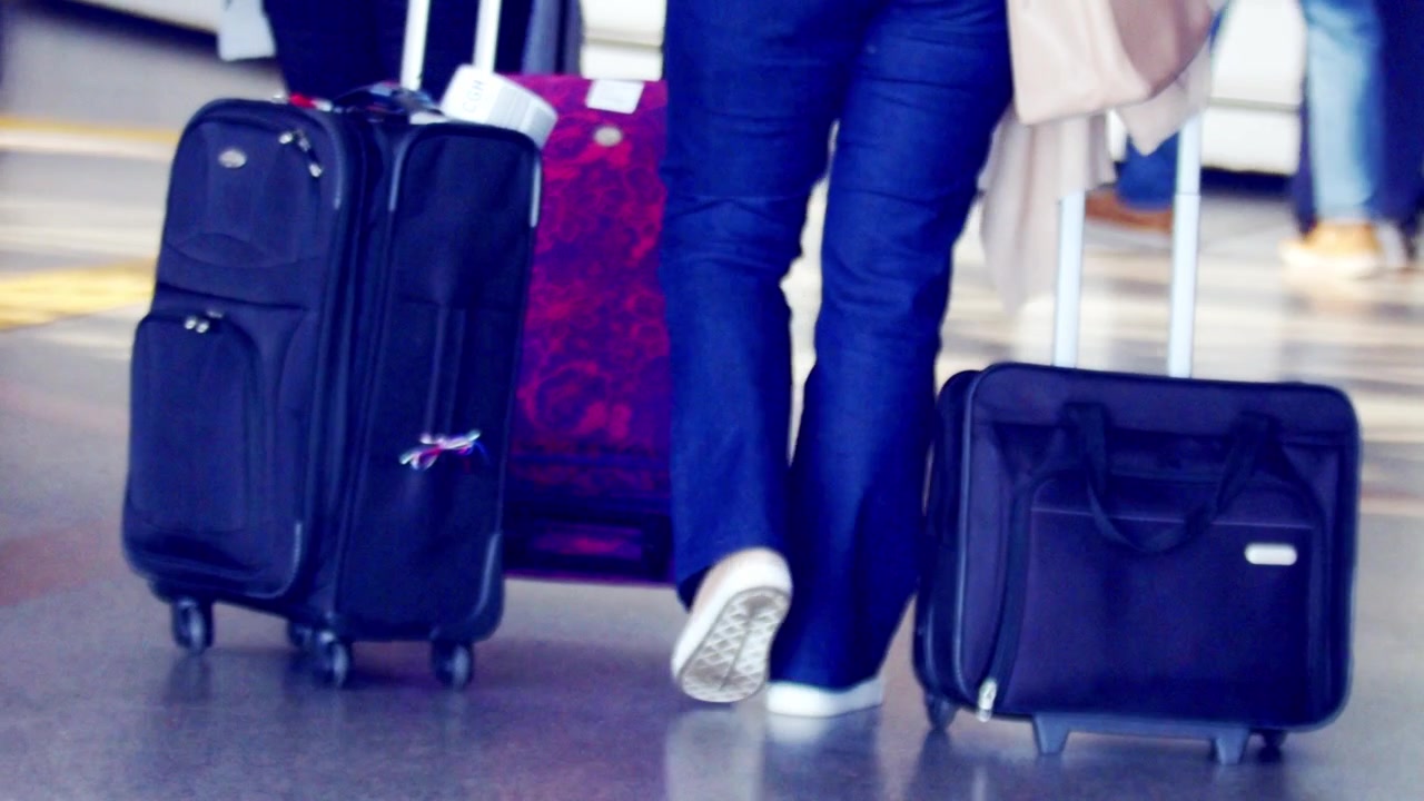 Traveler's legs walking in an airport, rolling luggage to board plane. Slow motion