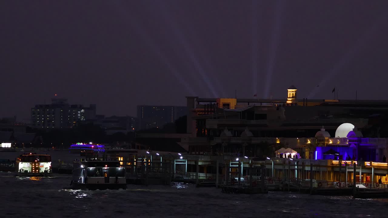 밤에는 활기찬 도시 조명과 반사에 의해 조명 된 차오 프라야 강을 따라 보트가 미끄러집니다.