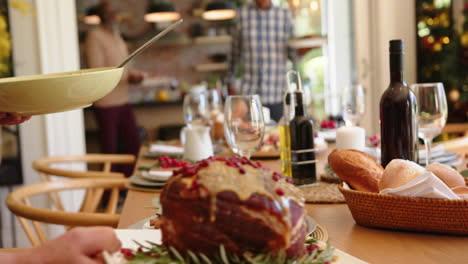 Happy-diverse-senior-male-and-female-friends-setting-food-on-christmas-dining-table,-slow-motion