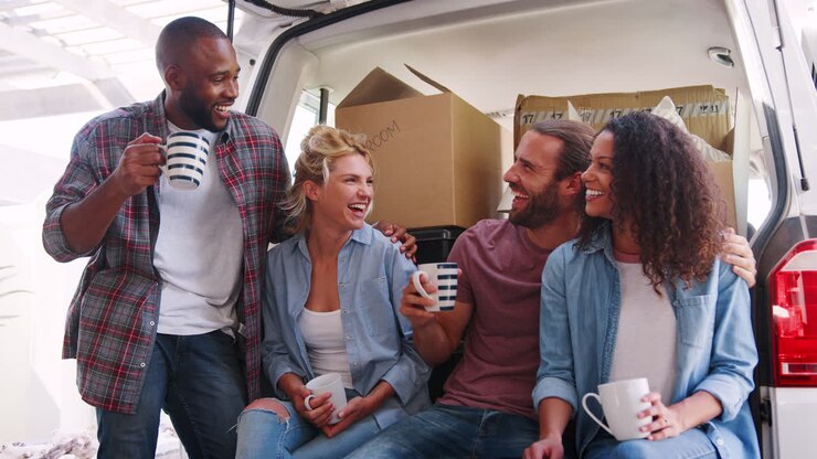Slow Motion Shot Of Friends Helping Couple To Unload Removal Truck On Moving Day
