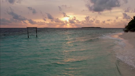 drone shot of maldives sunset and swing in ocean, panoramic sky and beach