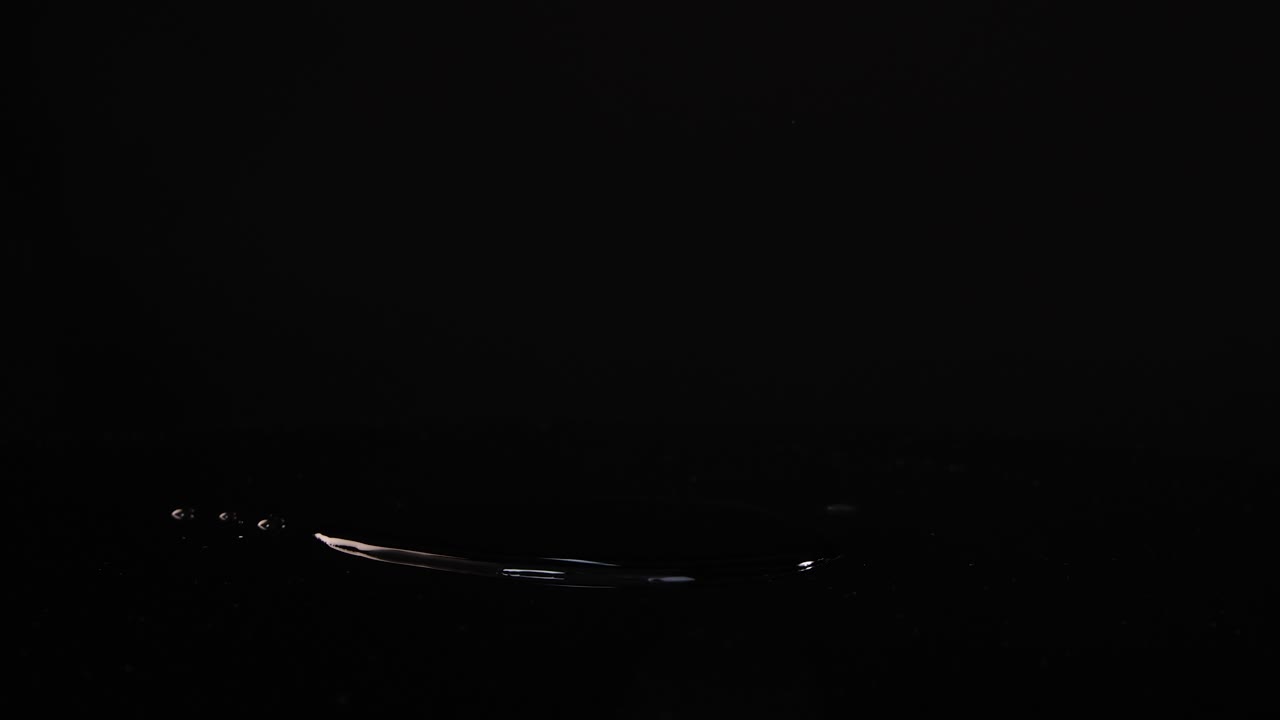 Lime slices fall and splash on a reflective black surface, captured in slow motion with dramatic lighting