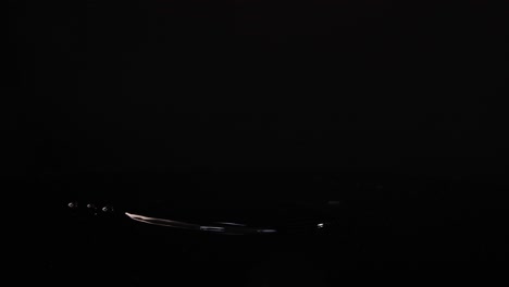 lime slices fall and splash on a reflective black surface, captured in slow motion with dramatic lighting
