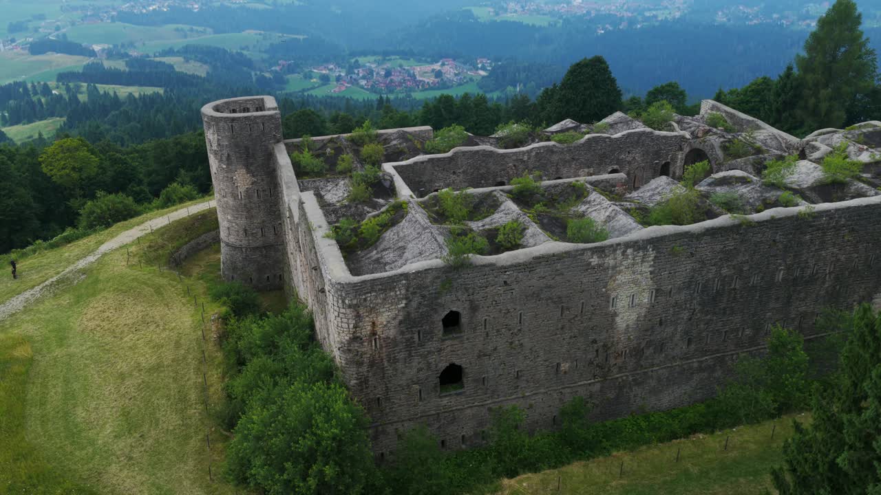 Aerial view of historic Forte Interrotto ruins on hilltop. Overgrown fortress surrounded by pine forest. For travel or history content, Asiago, Italy