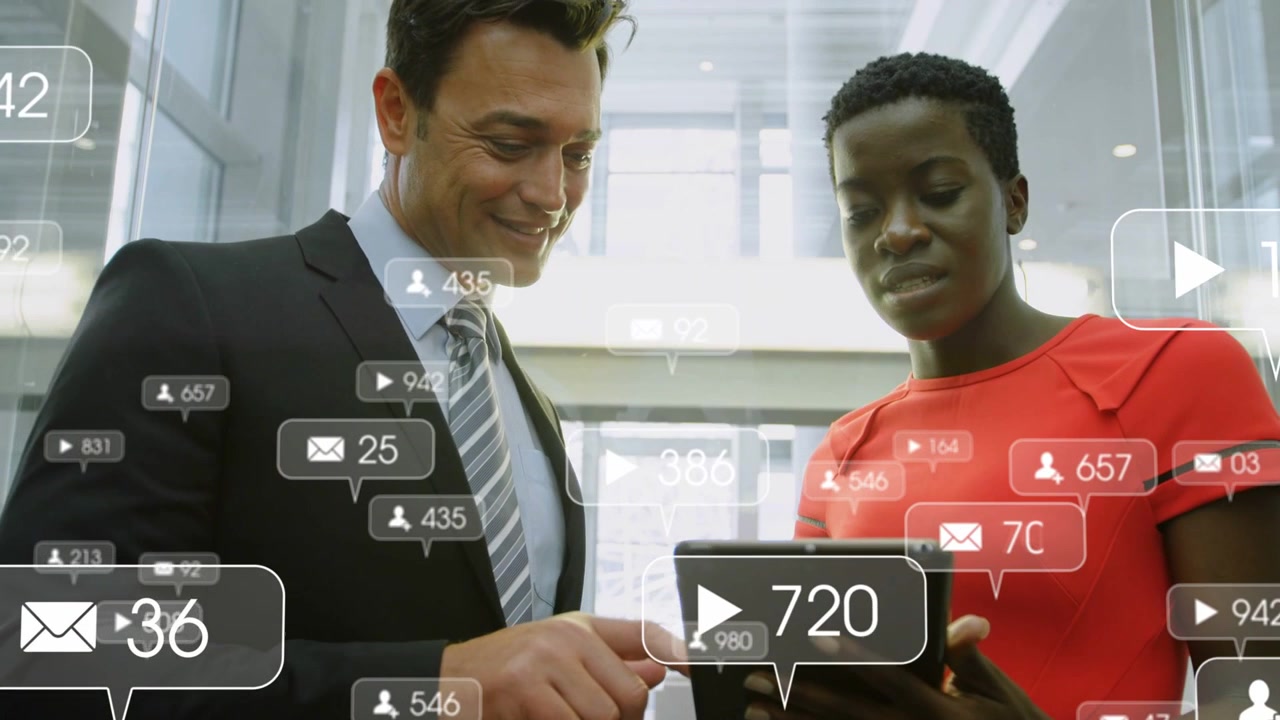 Man pointing and woman tapping tablet in atrium, causing notifications to multiply for marketing