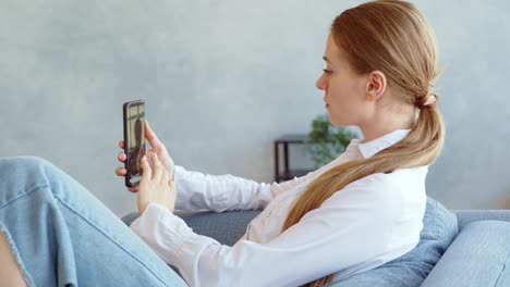 mujer usando un teléfono inteligente en un sofá