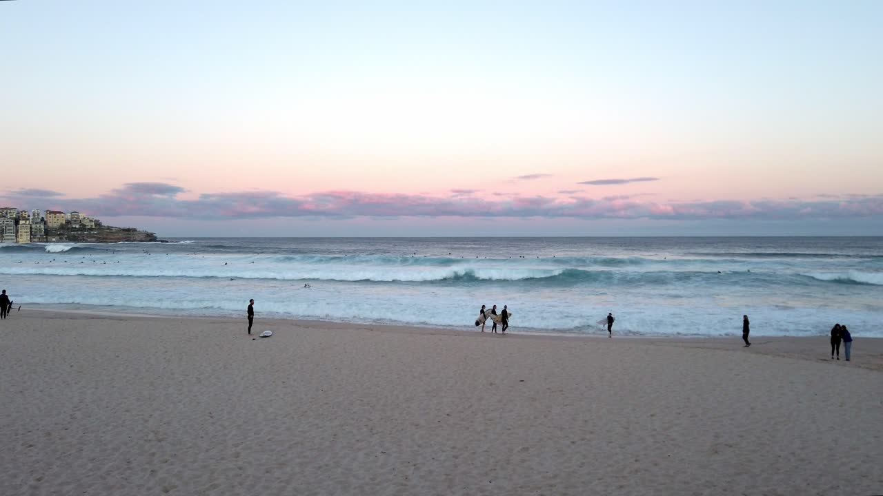 일몰 시 뉴사우스웨일즈 시드니의 본다이 해변에서 파도를 바라보는 해변가의 서퍼들