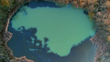 Aerial-Birds-Eye-View-Of-Green-Lake-Surrounded-By-Forest-Trees