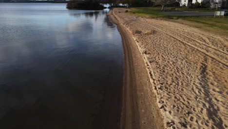 drone shot along the empty grassy sandy shore with tire tracks and gentle waves pt 2