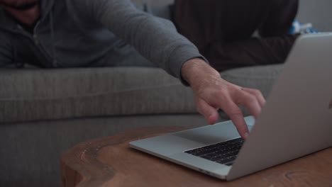 el joven se acuesta cómodamente en el sofá y trabaja en la computadora
