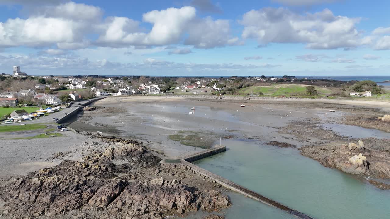 puerto de bordeaux guernsey alto tiro de drone en círculo lejano que muestra todo el puerto en un día soleado con barcos en duras y secas y vistas sobre la playa y hacia el norte de guernsey