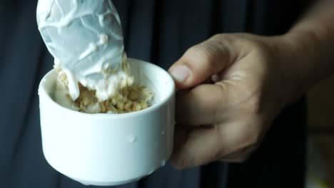 poniendo yogur en granola musli en un tazón