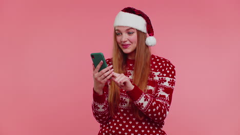 Erwachsenes-Mädchen-Im-Roten-Weihnachtspullover-Schaut-Auf-Smartphone-Display-Und-Freut-Sich-Aufrichtig-über-Erfolg-Und-Glück