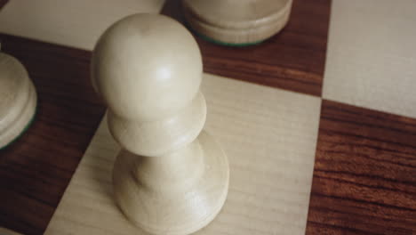 tilt down perspective of white queen and pawn chess piece in position for battle, closeup