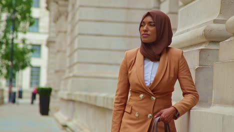 portrait of muslim businesswoman wearing hijab and modern business suit standing outside city office buildings 2