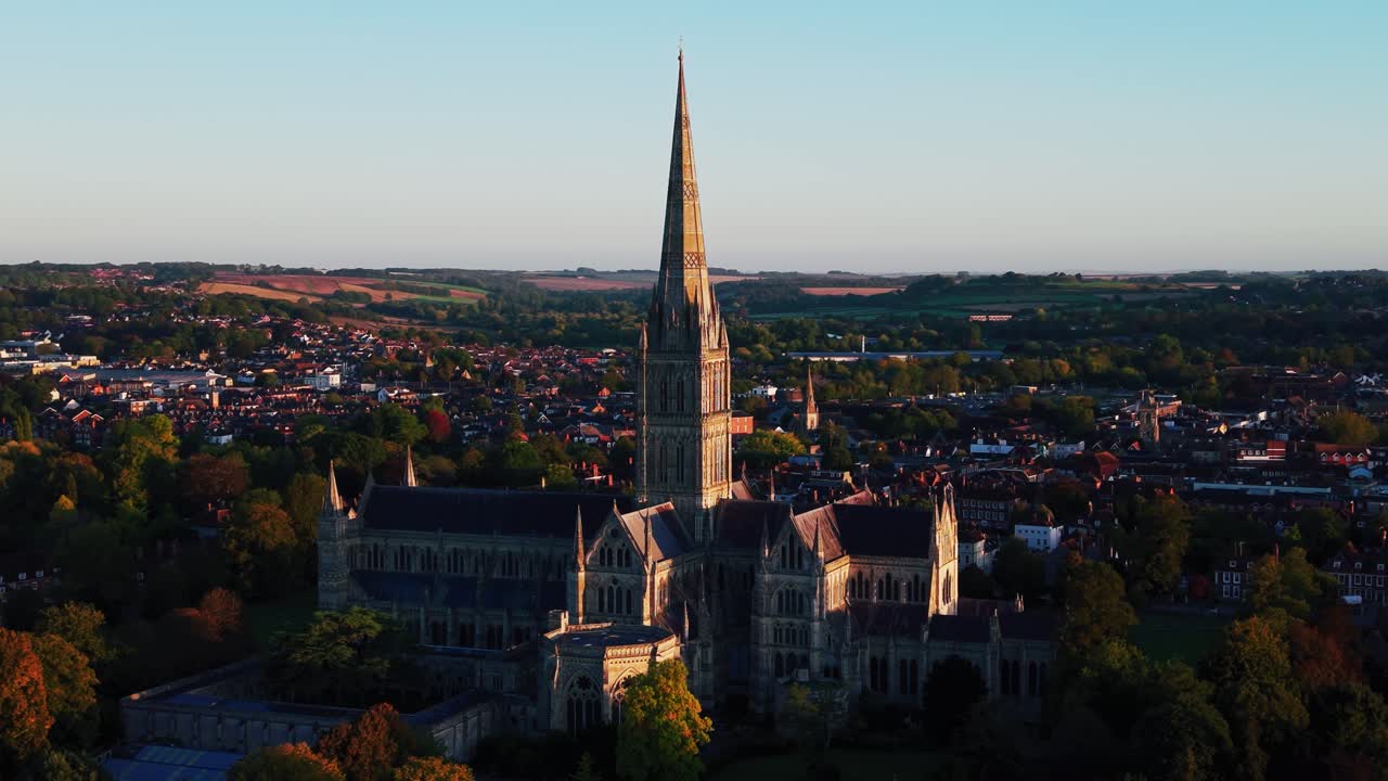 Ripresa aerea con drone della Cattedrale di Salisbury che domina lo skyline della storica città di Salisbury nel Wiltshire, Inghilterra, durante la calda luce serale