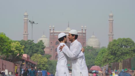 two indian muslim men hugging each other on eid festival in front of jama masjid delhi