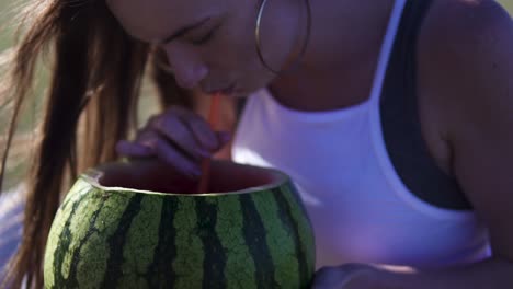 mujer sosteniendo sandía y bebiendo de ella, pasándola bien