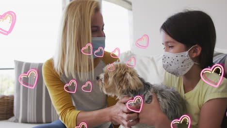 animación de corazones sobre mujer caucásica y su hija con máscaras faciales jugando con un perro mascota