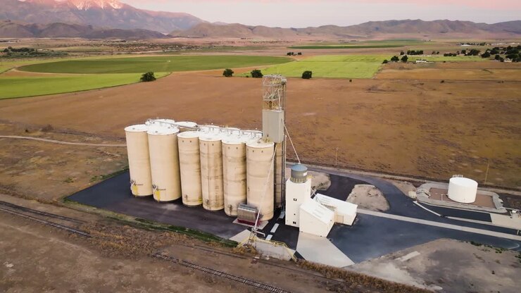 Grain silo elevator in a farming community and valley in Utah - aerial parallax