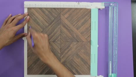 cutting a paper with a board tool, wooden pattern paper trim and score, closeup on violet background
