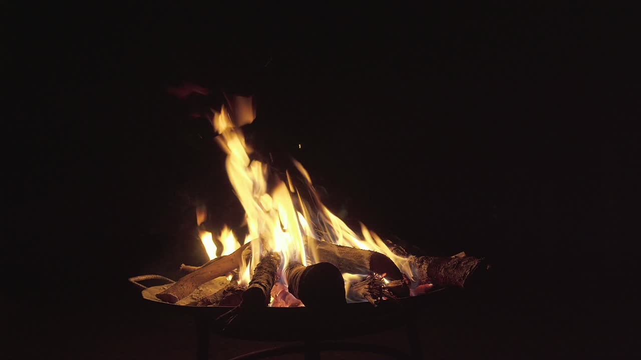 Scatto statico di un falò scoppiettante con braci incandescenti e fiamme giallo brillante sullo sfondo nero intenso di una notte rurale nella riserva naturale di Cerrado a Goiás, in Brasile