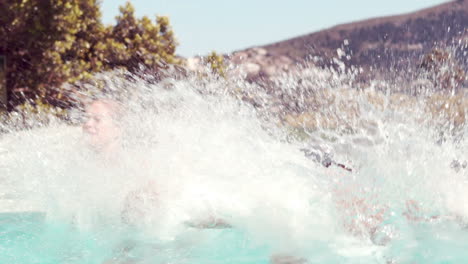 Couple-jumping-into-swimming-pool-holding-hands