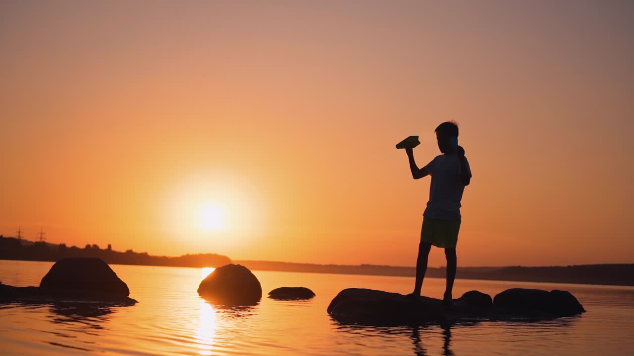 The boy throws a paper airplane. Beautiful sunset. Origami.