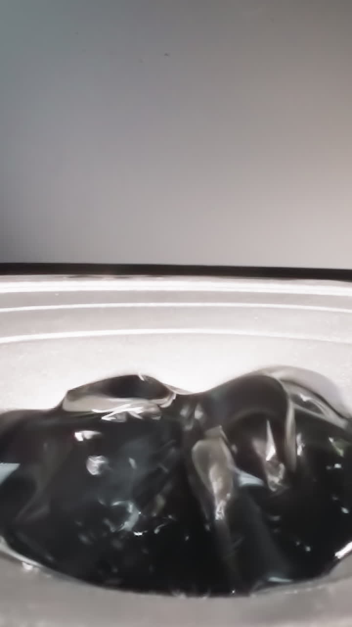 Slippery hyaluronic acid bouncing and shaking on loud speaker while playing music. Dense gooey substance reflecting bright studio light macro