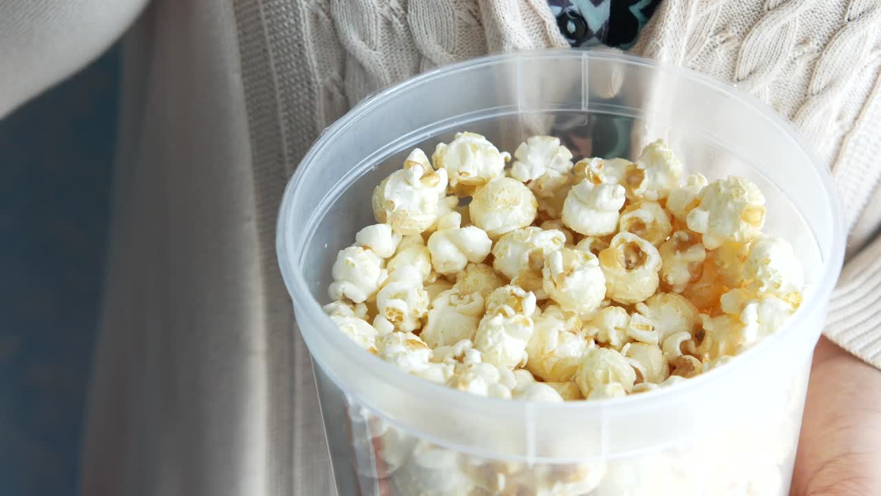 Kvinne som spiser popcorn fra en beholder