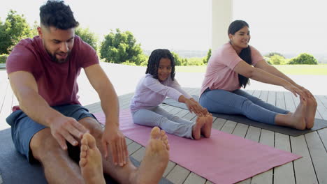 family enjoying outdoor yoga session on mats, smiling and stretching together
