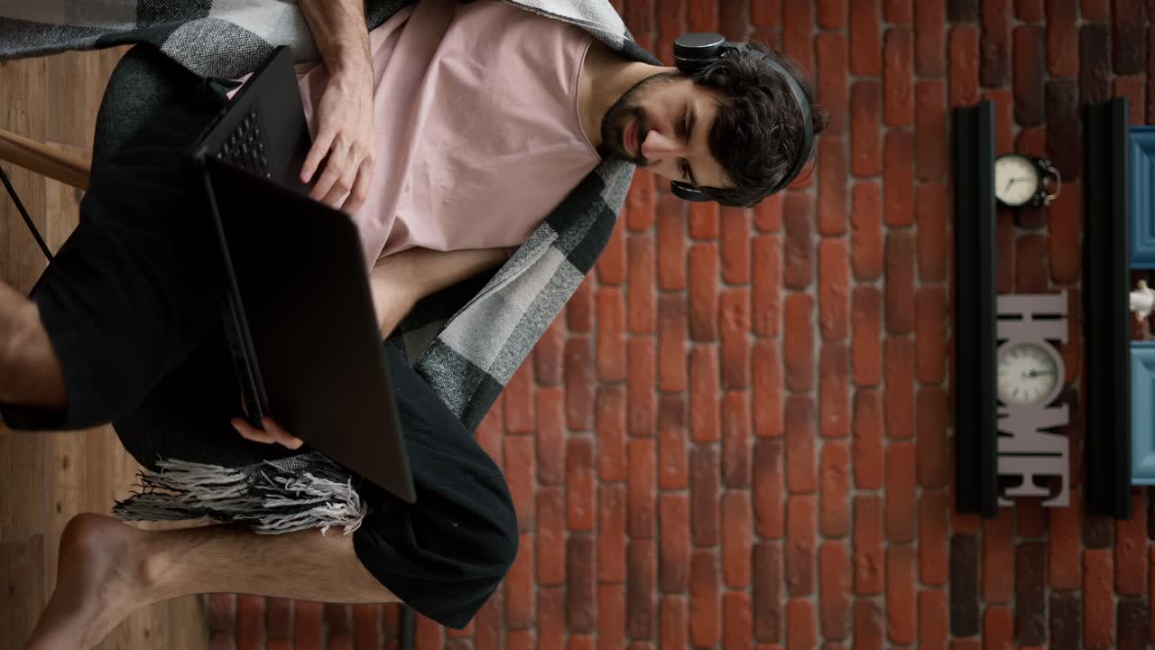 hipster freelancer trabaja en computadora portátil y auriculares relajado en casa