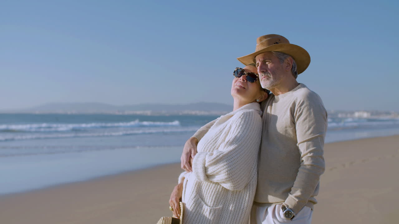 pareja mayor romántica hablando y riendo juntos mientras se abrazan en la playa
