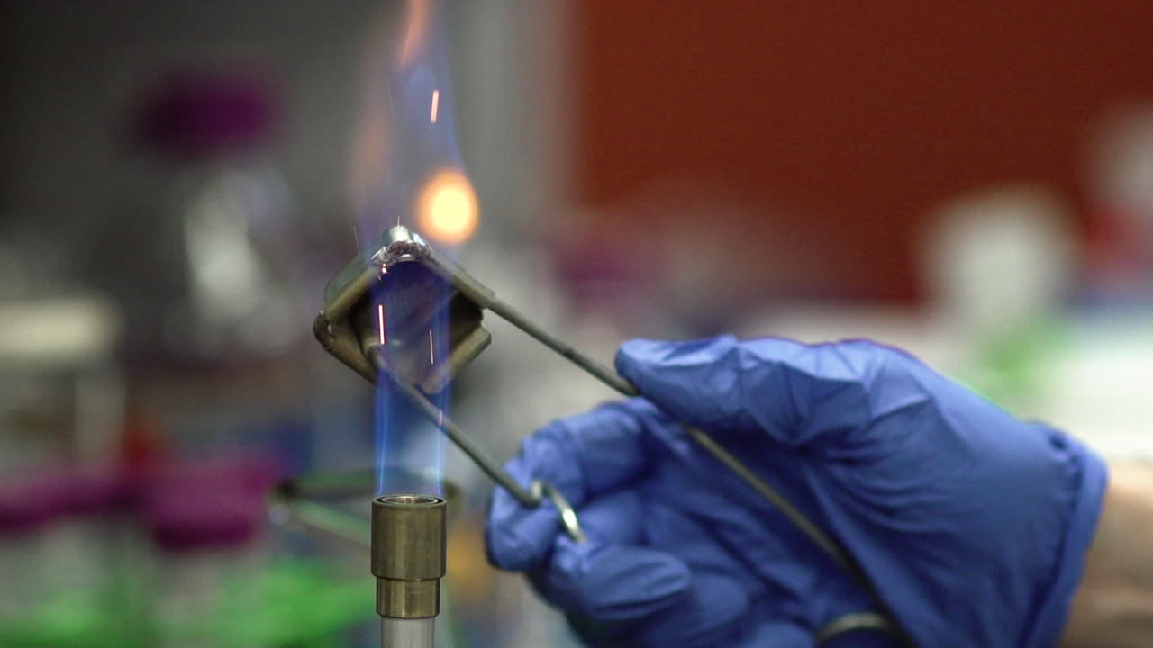 A lab technician uses a lighter to ignite a Bunsen burner.