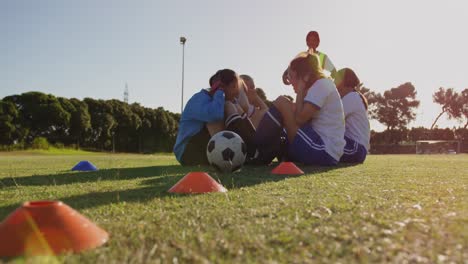 female soccer players doing sit up exercises while captain gives training on soccer field. 4k