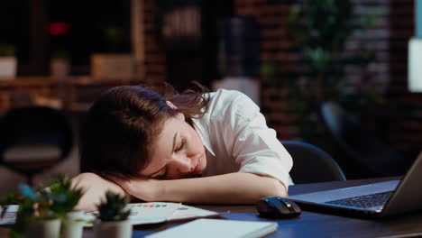 sleepy employee asleep on computer desk late at night in brick wall office