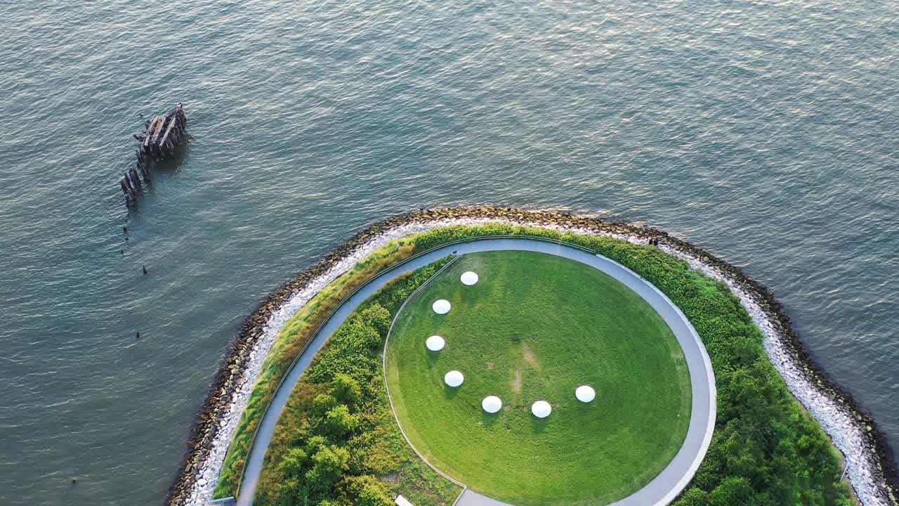 공중 위에서 아래로 촬영한 다음 둥근 녹색 공원 지역에서 위로 기울어 황금 시간 일몰 - 백그라운드에서 뉴욕시의 스카이라인을 나타냅니다.