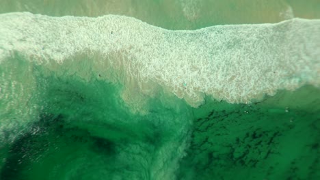 aerial view of a beach with waves and people surfing